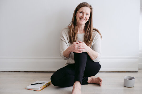Mature woman sitting on floor enjoying tea or coffee and journaling