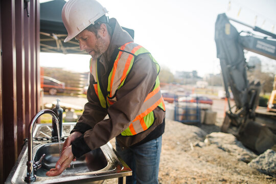 Construction worker washing his hands outside on the jobsite.