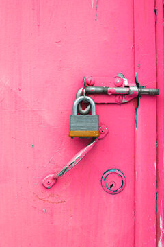 Close up of padlock attached to a bolt on a bright pink door