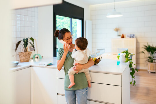 Mother talking on the phone with baby at home