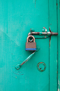 Close up of padlock attached to a bolt on a green door