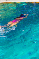Woman traveler in bikini is swimming in pool