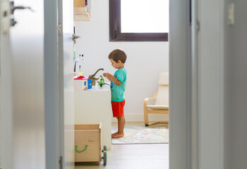 Little Boy Playing With Dinosaurs In Playroom