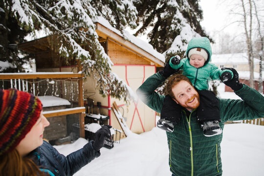 Young family spending time together in the snow dong shoulder ri