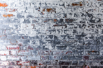 Close-up on a once clay brick wall abstractly painted in white and grey paint.