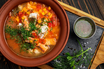 Ukha royally, fish soup, from several varieties of fish, in a clay plate, on a wooden board