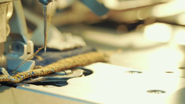 Close-up shot of sewing machine opening buttonhole for jeans.