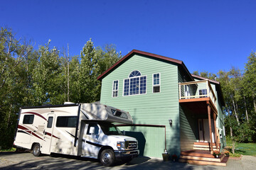Two-story, green house with motorhome parked in front