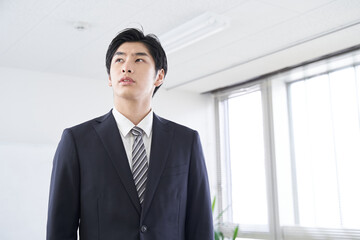 会議室で考え事をする日本人男性ビジネスマン