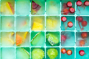 Pieces of berries, cucumbers and mangoes frozen in a silicone mold. Edible ice cubes close-up.