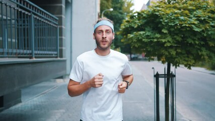 Attractive male runner preparing for marathon jogging on streets looking very healthy and confident. Sportsman. Cardio exercising. Active lifestyle. Cityscape.