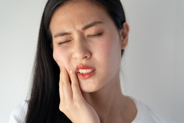 Teeth and gum problem concept. Asian young woman touching cheek and feeling toothache and pain face...