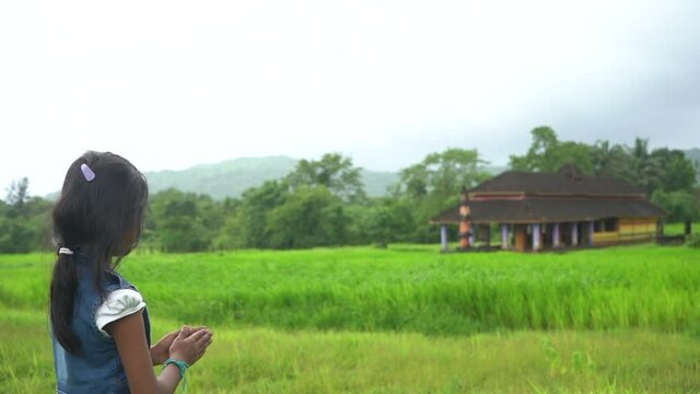 little girl praying  near temple  farm malvan maharashtra back shot.