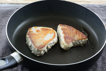 Cooking fresh ahi tuna fillet steaks with olive oil in frying pan