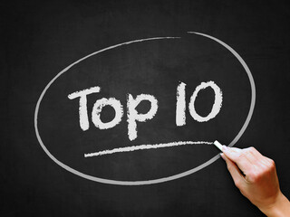 A hand writing 'Top 10' on chalkboard for ranking position theme.