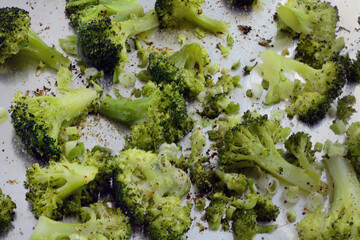 Roasted broccoli florets with green onions and spices on aluminum foil