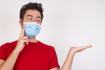 Funny Young caucasian man with short hair wearing medical mask standing over isolated white background with short hair holding open palm new product. I wanna buy it!