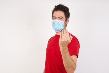 Young caucasian man with short hair wearing medical mask standing over isolated white background inviting to come with hand. Happy that you came