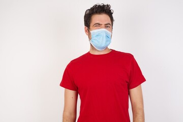 Young caucasian man with short hair wearing medical mask standing over isolated white background...