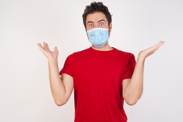 Young caucasian man with short hair wearing medical mask standing over isolated white wall celebrating crazy and amazed for success with arms raised and open eyes screaming excited. Winner concept