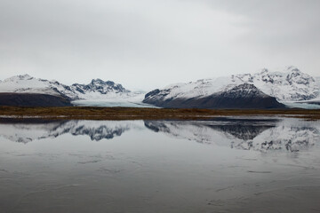 Snowy mountains and glaciers reflecting in still lake