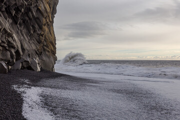 ocean wave and basalt rock formations on Icelandic black beach