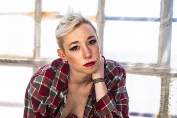 Portrait of a young urban woman with short blonde hair and casual attire.