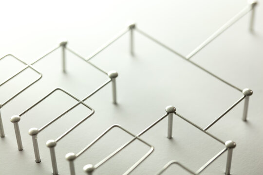 Hierarchy, command chain, company / organization structure or layer and grouping concept image. Top down structure made from chrome wires and silver nails and wire on white. Shallow depth of field.