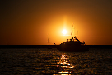Obraz premium Motor yacht in the seaport against the backdrop of the sunset.
