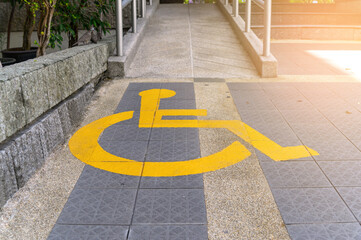 Yellow painted handicapped sign traffic symbol on the floor in front of ramp way for support...