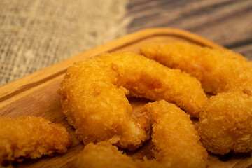 Atlantic prawns fried in batter on a wooden serving Board. Close up.