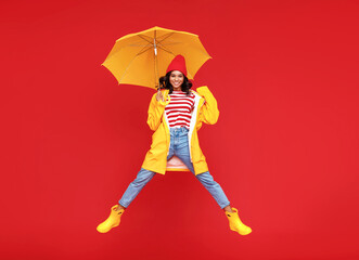 Happy ethnic female jumping with umbrella.
