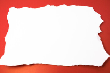 a white torn sheet of paper with space for text lies horizontally on a red background