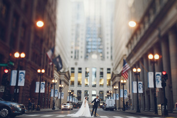 Fototapeta na wymiar Elegant bride in a white dress and veil. Handsome groom in a blue suit. Couple in a big city