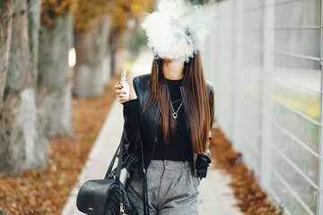 stylish girl smoking an e-cigarette as she is walking through the city