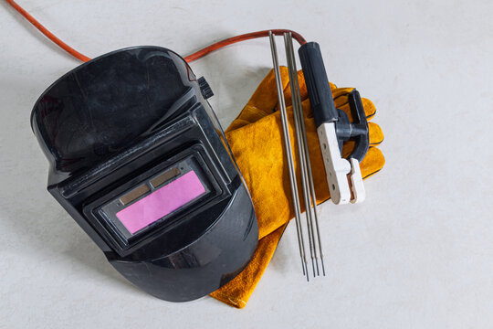 Welding equipment including leather welding gloves, welding mask, hand held welding electrode on  floor