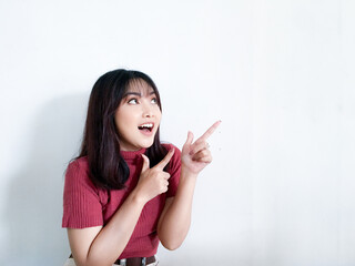 Happy and smile face with smile of young Asian girl in red shirt with hand point on empty space.