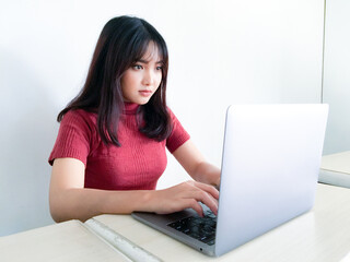 Asian beautiful girl serious or thinking in the front of laptop on the isolated white background