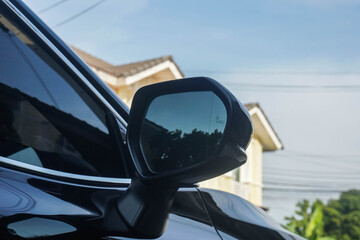 close up side view mirror of the black luxury car with blind spot monitor system