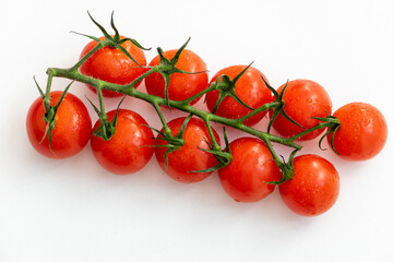 a vine of fresh tasty cherry tomatoes on a white table