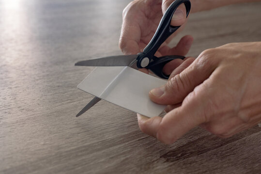 male hands with scissors cut the payment card. concept of liquidation, destruction of deactivation, decommissioning