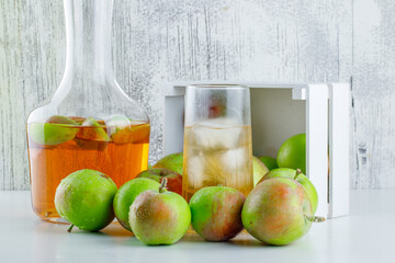 Scattered apples from a wooden box with drink side view on white and grungy background