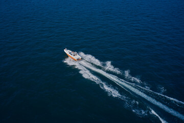 Top view of a white boat sailing in the blue sea. A boat with a motor on blue water. Aerial view luxury motor boat.  Top view of the boat.
