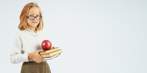 Teenager girl in glasses holding an apple and a book in her hands. Isolated background.