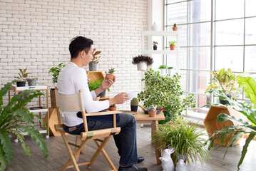 back side asia handsome man enjoying in the garden sitting in greenhouse relaxing with coffee wiyh copy space