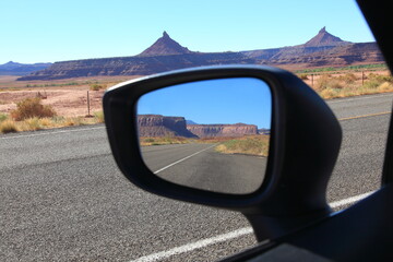 Scenic view of road leading to The needles with mesas reflected in a car side view mirror in Canyonlands National Park Utah, USA