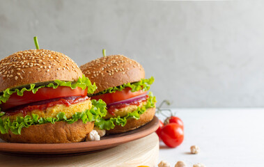 Fresh vegan chickpea burger with onion, tomatoes and lettuce. The concept of healthy and vegetarian food. Place for text. Plant based food concept.
