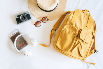 Fototapeta na wymiar Travel accessories with straw hat, sunglasses, bagpack, camera, headphone and passport on bed in hotel room. Travel, relaxation, journey, trip and vacation concepts. Top view