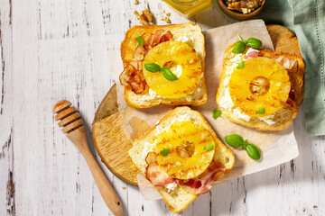Healthy breakfast or snack, snacks. Toast with caramelized pineapple, bacon, nuts, and ricotta on the kitchen table. Top view flat lay background. Copy space.