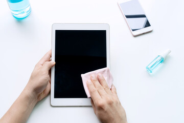Man hands cleaning tablet with microfiber fabric and alcohol spray. Disinfection daily use item to reduce an infection, preventive measures during the period of pandemic concept